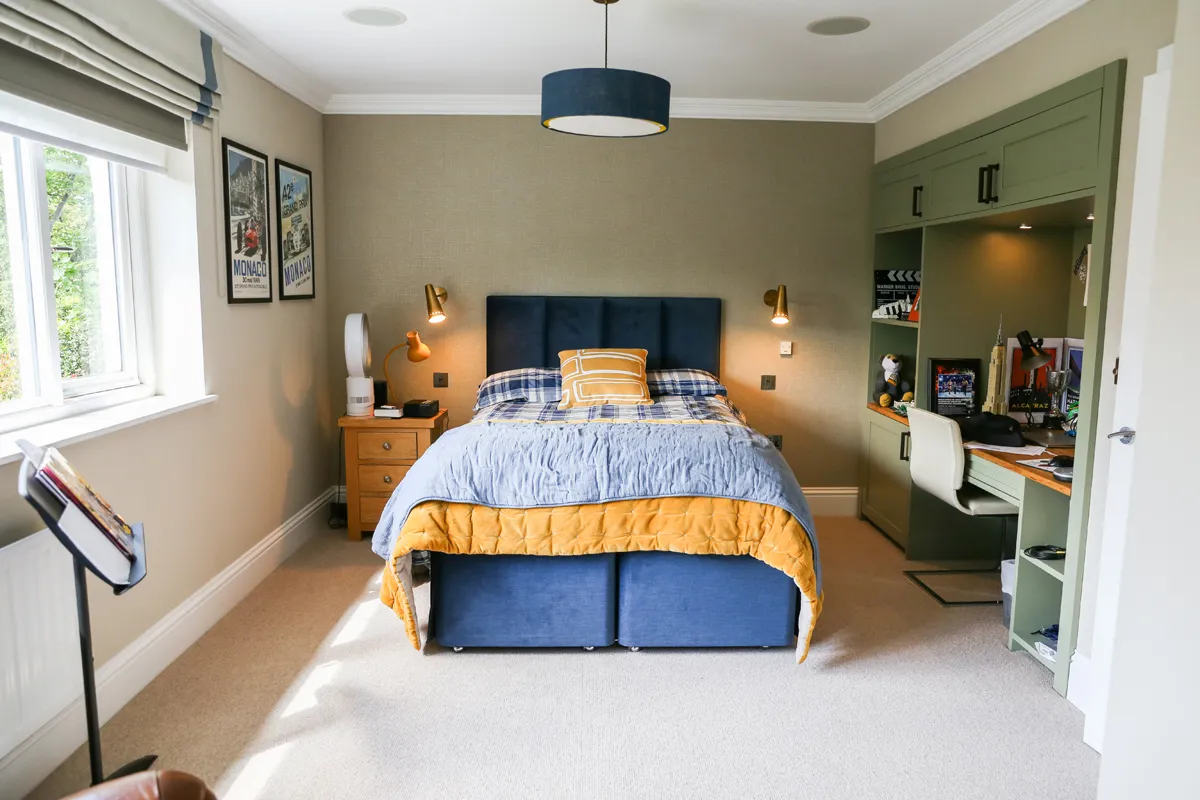Bedroom interior with fitted storage and a navy upholstered bed
